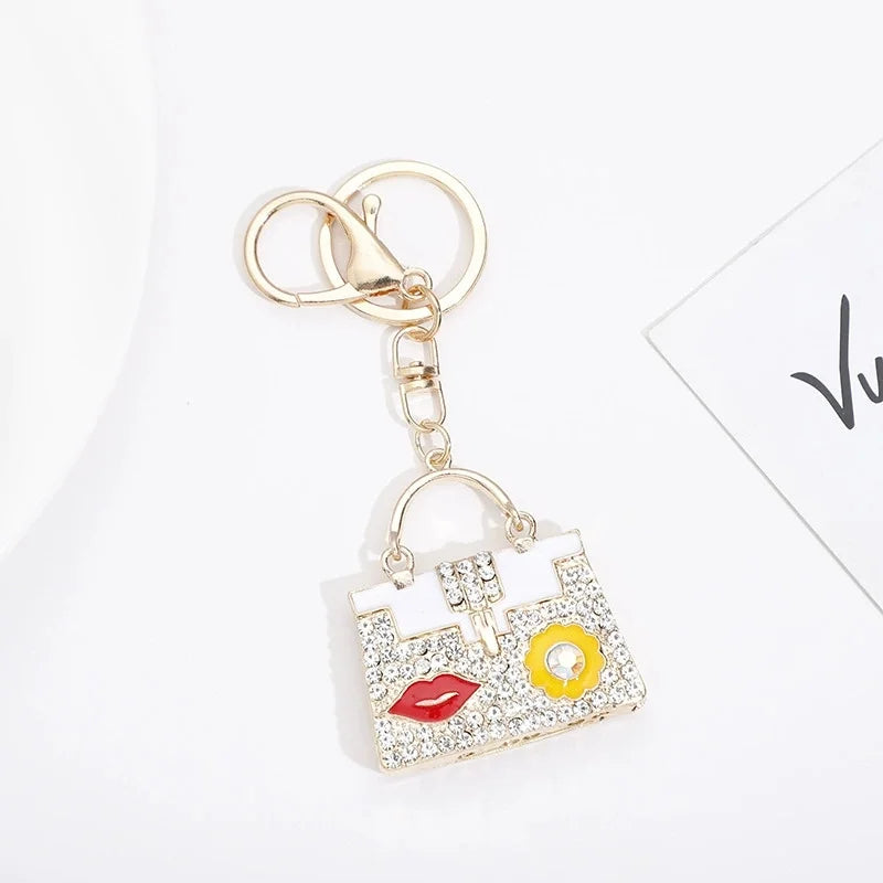 Gold chain keychain featuring a crystal rhinestone handbag charm with a white and yellow design