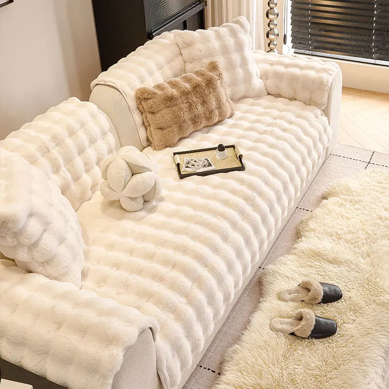A cream plush sofa cushion cover featuring quilted texture and decorative faux fur accents.