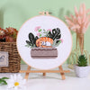 Embroidery kit featuring pre-printed floral and cat designs displayed on a wooden board.
