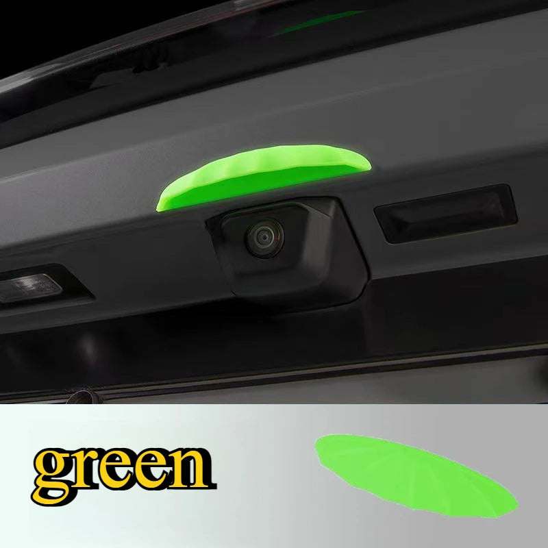 A close-up view of a green rain shield for a universal car rear camera mounted on a vehicle's interior panel.