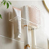 Wall-mounted acrylic organizer holding a white hairbrush and a pink round brush.