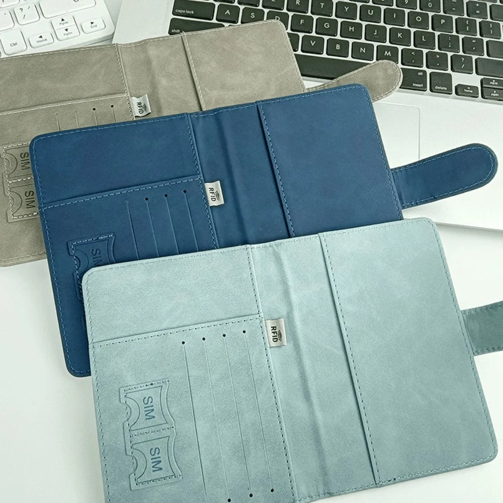 Porta documentos de cuero azul y verde menta con bloqueo RFID, junto a un teclado de portátil.
