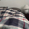 A close-up view of black, red, and white plaid bedding fabric with a subtle texture.
