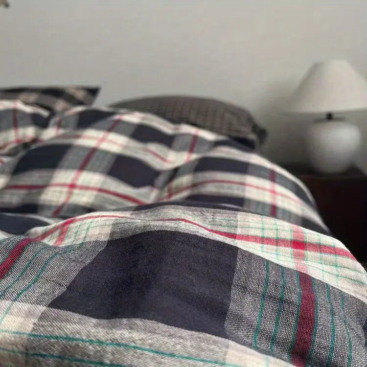 A close-up view of black, red, and white plaid bedding fabric with a subtle texture.