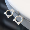 A close-up view of a white silicone toilet lid lifter with self-adhesive hooks attached to the side.