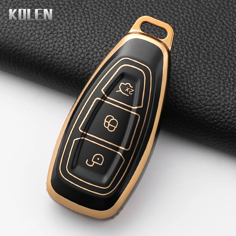 A gold-toned silicone car key fob cover with a black finish, shown against a dark background.