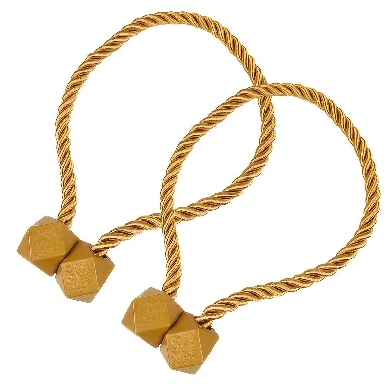A set of two golden braided rope curtain tiebacks with brass pyramid accents.