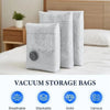 A set of white breathable stackable solid vacuum storage bags displayed on a bed with a wooden nightstand in the background.