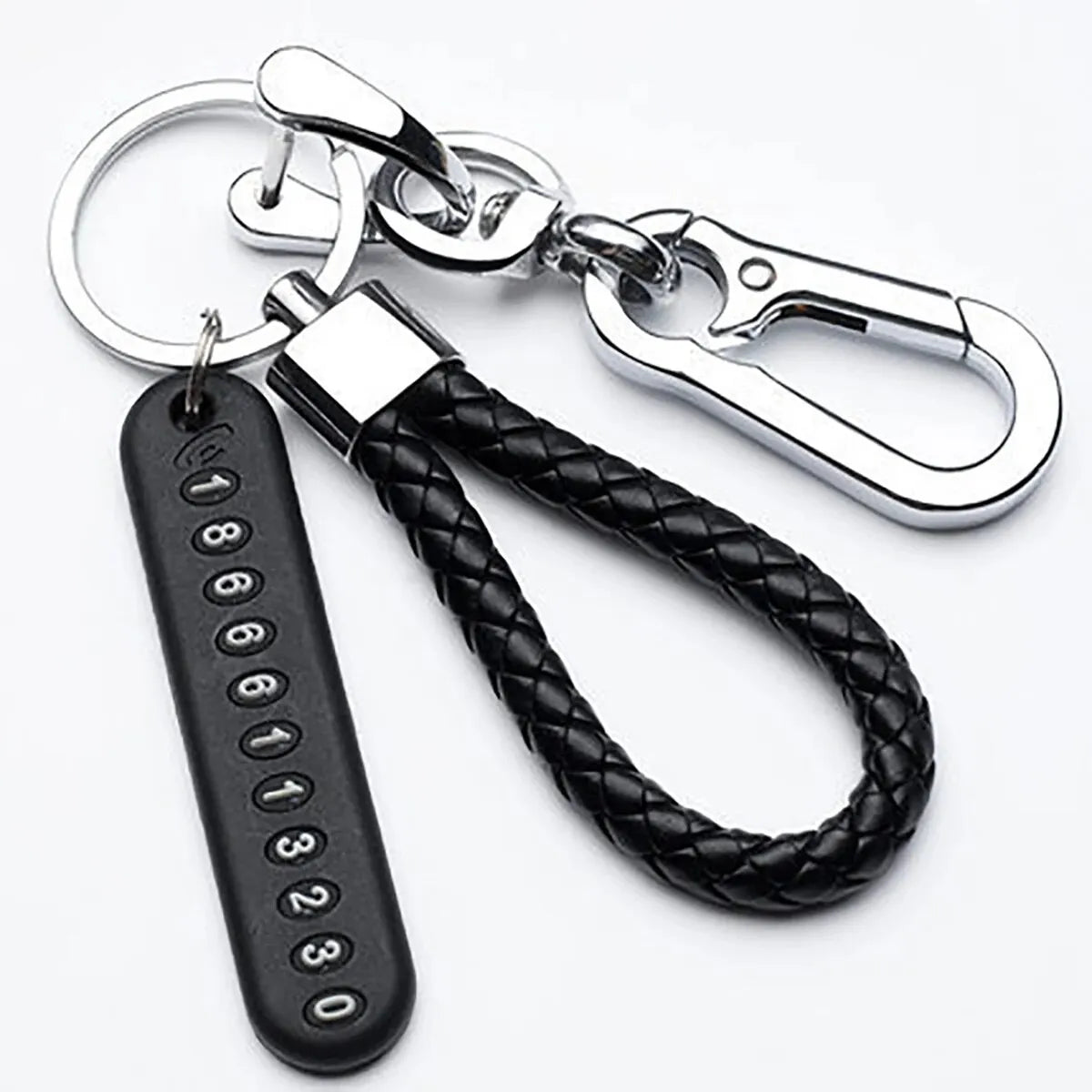 Silver keychain featuring a personalized phone number engraved on a black tag and attached to a braided leather rope.