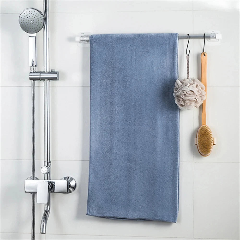 A blue towel is hanging on a metal rack next to self-adhesive curtain rod hooks and a wooden brush.