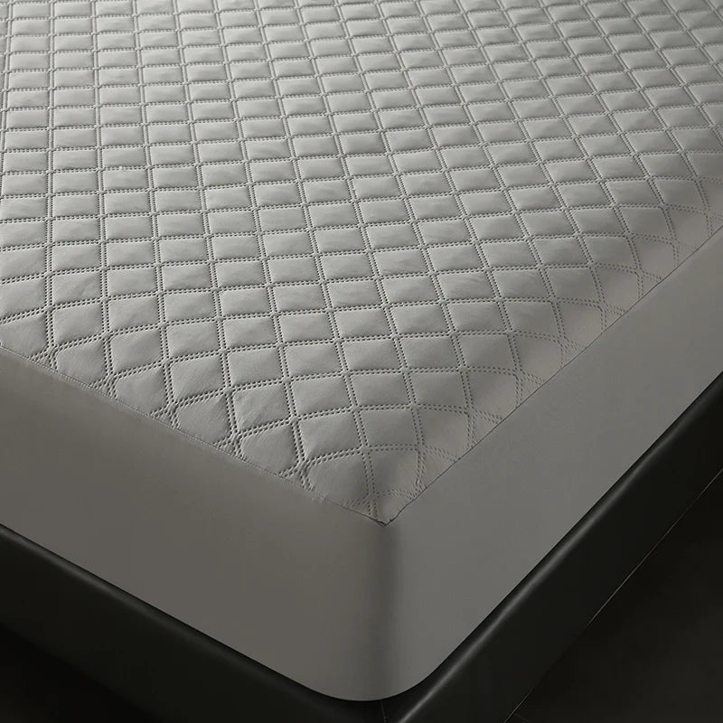 A close-up view of a gray quilted waterproof mattress protector with deep pockets.