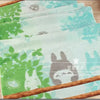 A stack of light green and teal embroidered cartoon face towels with natural wood trim.