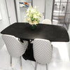 A dark wood grain table set with white upholstered chairs and a vase of white flowers.