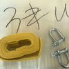A yellow heavy-duty vehicle recovery towing strap coiled on a light surface next to metal tow shackles.