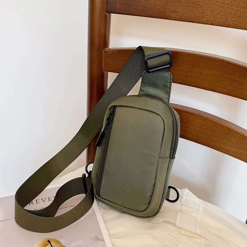 Olivgrüner vielseitiger Unisex-Crossbody-Rucksack auf einem Holzstuhl.