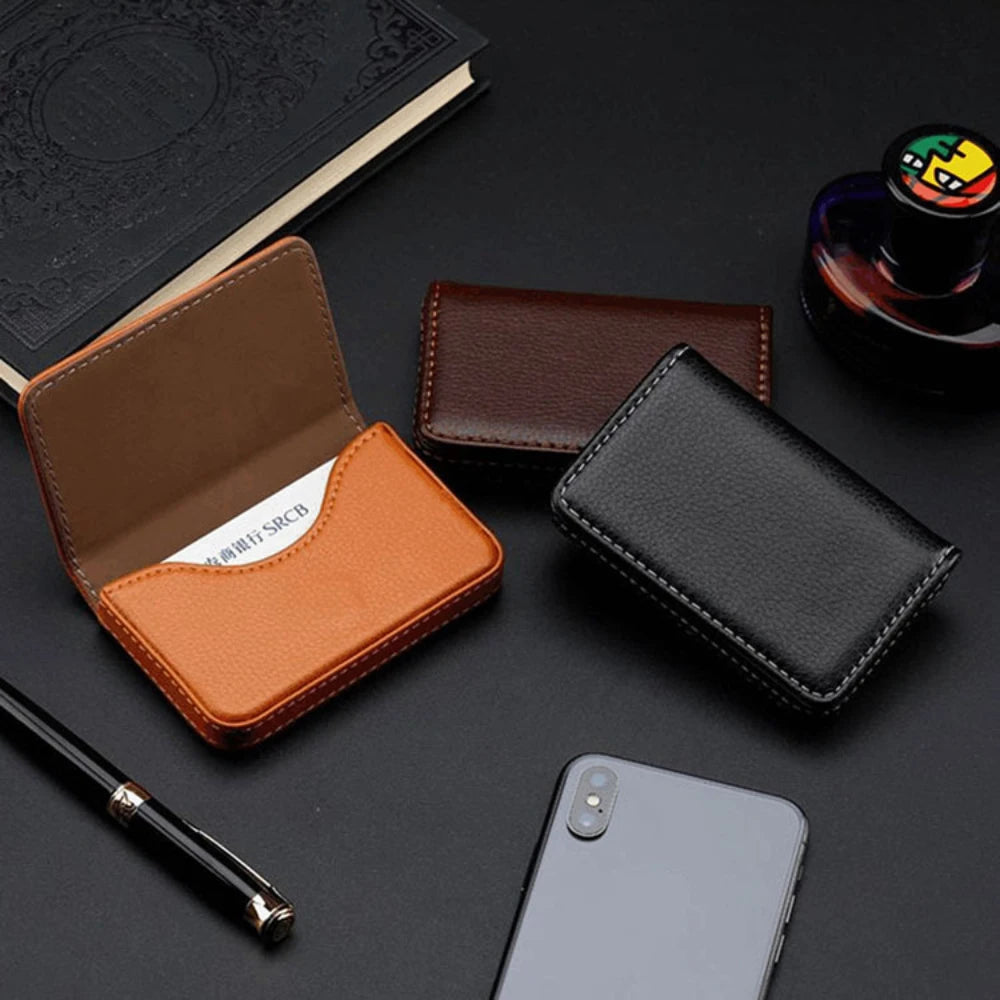 A collection of brown and black stitched PU leather card holder wallets, a pen, and a smartphone on a dark surface.