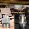 A set of solar-powered flameless LED tea lights in glass holders displayed on a wooden surface.