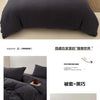 Ein Set aus dunkelgrauen, faltigen Bettbezügen und Kissen auf einem Bett.