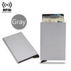 A gray slim metal RFID blocking card holder with a pop-up design, shown next to a credit card.