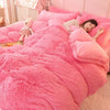 A pink plush mink velvet duvet cover set with sheets featuring a white stuffed animal on the bed.
