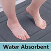 Close-up of a foot resting on a dark gray absorbent mat, demonstrating the non-slip texture.