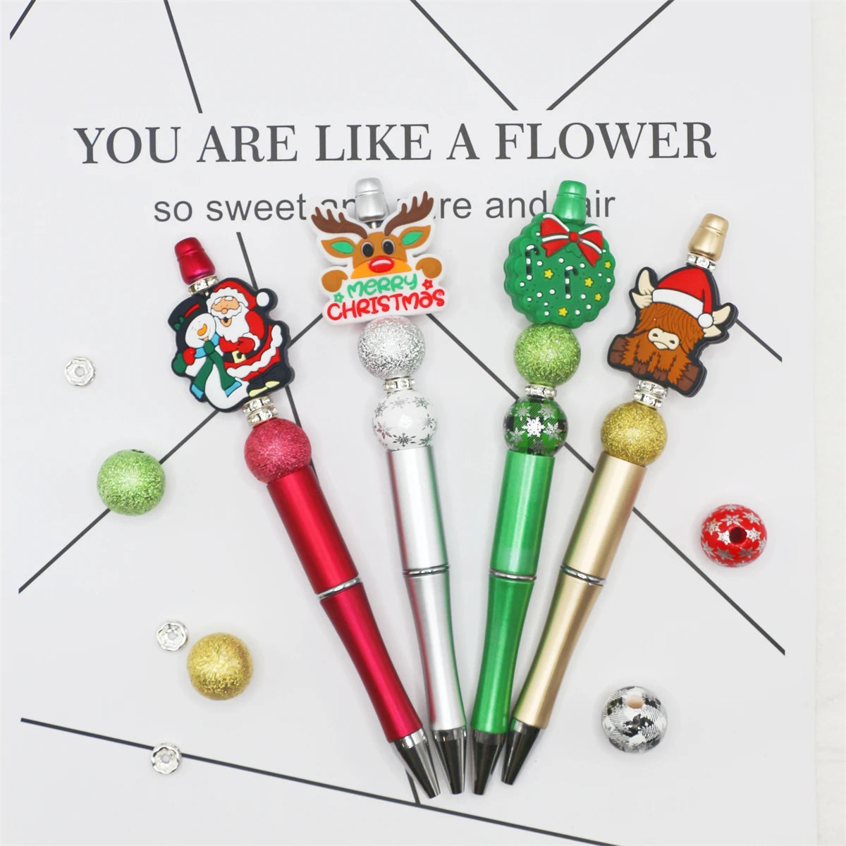 A DIY beaded ballpoint pen craft kit featuring a Christmas bead assortment and various colored pens.