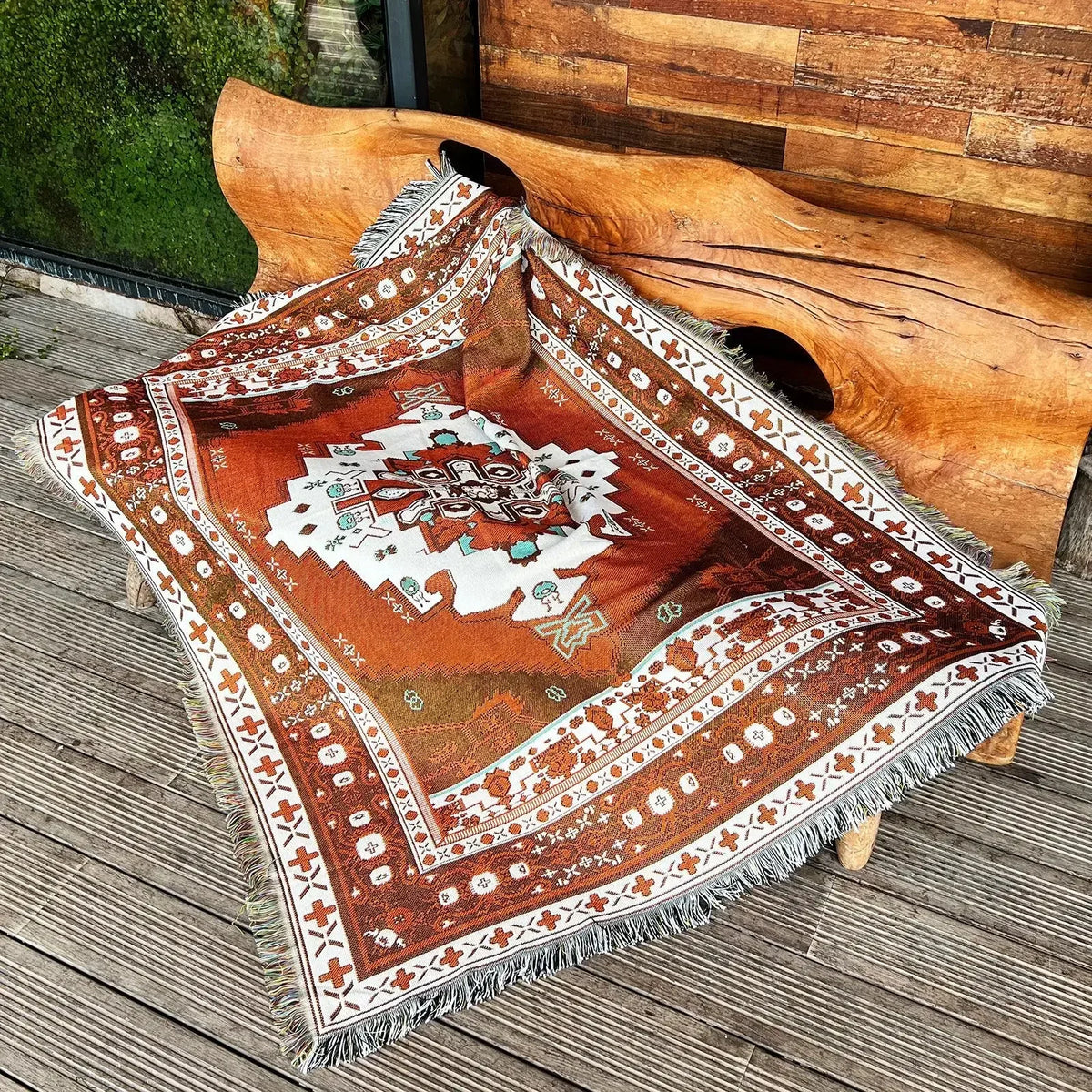 A patterned bohemian jacquard woven throw blanket with earthy tones draped over a large wooden antler.
