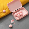 A pink storage box with six pink round clips rests on a yellow fabric surface.