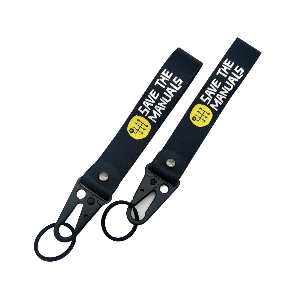 Black leather strap with yellow text Save The Manuals and a clasp keychain.