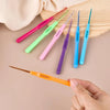 A set of seven aluminum alloy crochet hooks in various colors and sizes displayed on a wooden surface.