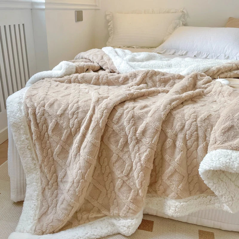 A beige double-layer fleece throw blanket draped over a bed with white bedding.