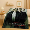 A dark green blanket featuring a collage of characters from the Supernatural TV show with the title text.