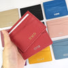 A hand holds a collection of genuine leather slim card holder wallets in various colors including black, pink, blue, and yell
