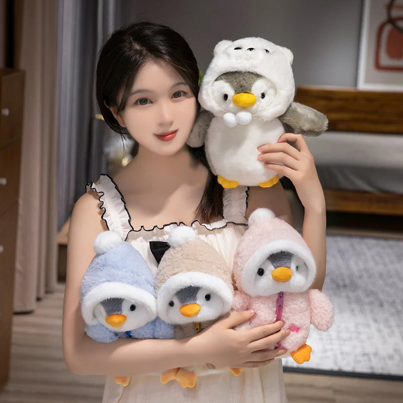 A woman holds a fluffy white penguin plush toy with an adorable hat and another small pink penguin plush toy.