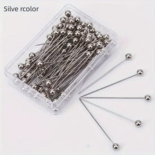 A clear plastic container filled with 100 silver-colored precision quilting pins for sewing and crafting.