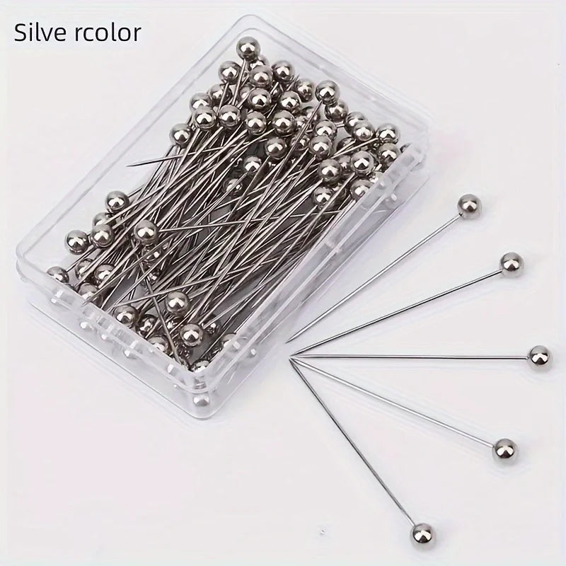 A clear plastic container filled with 100 silver-colored precision quilting pins for sewing and crafting.
