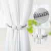 Silver braided pearl magnetic curtain tie-back clips shown on a white fabric backdrop.