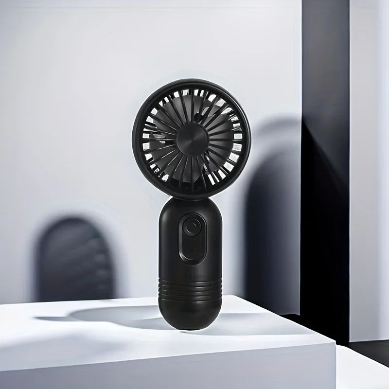 A black mini USB rechargeable handheld fan with a circular grille is displayed on a white surface.