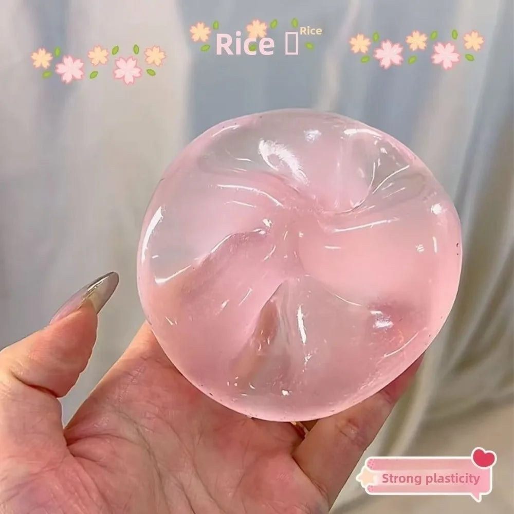 A hand holds a translucent pink stress ball made of rice, demonstrating strong plasticity.