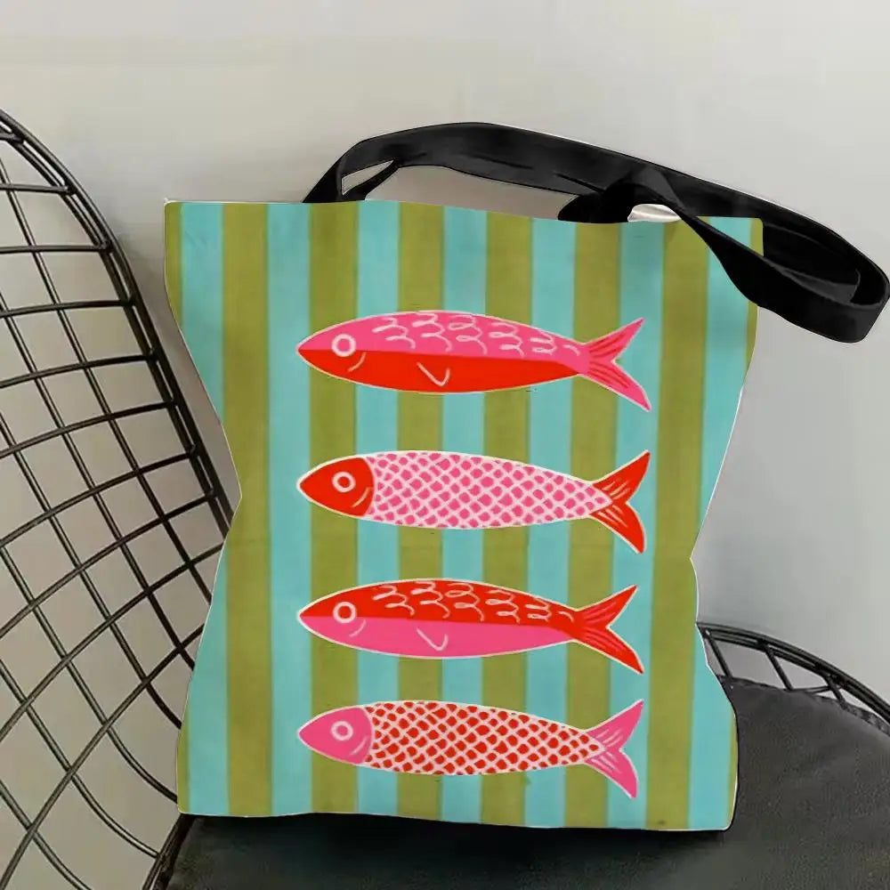 A canvas tote bag featuring a vibrant print of pink and red sardines on a light teal background.