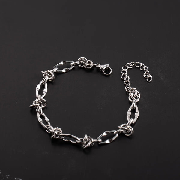 A silver titanium steel chain bracelet with knot details laid out on a dark background.