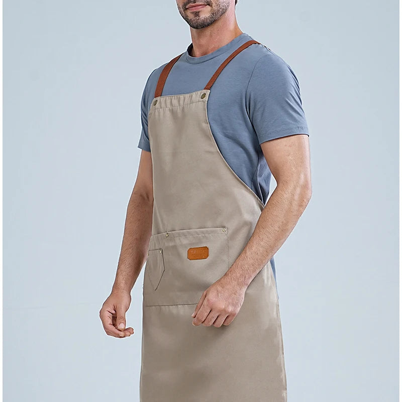 A man wearing a beige waterproof kitchen apron over a gray t-shirt.