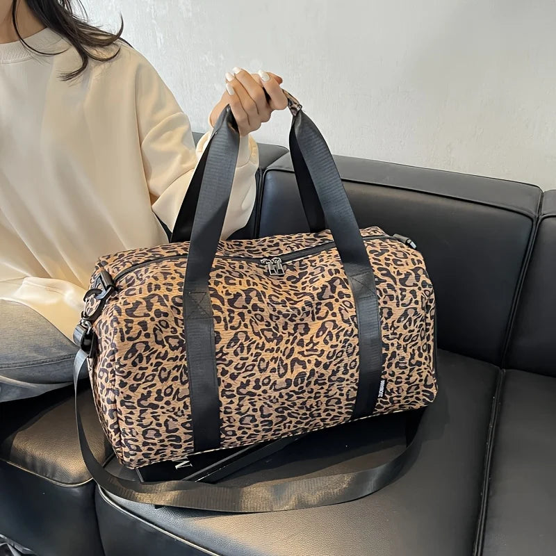 A leopard print weekender tote bag with black straps resting on a dark leather couch.