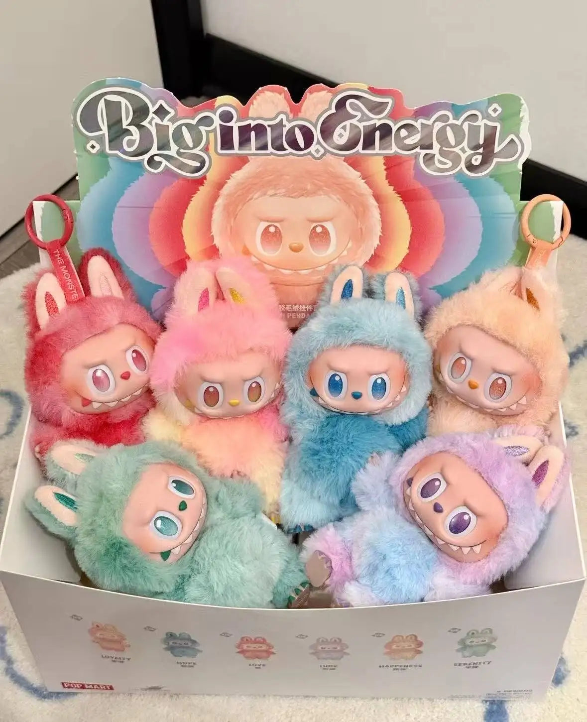 A collection of Labubu Big Into Energy plush dolls in various colors including pink, orange, blue, and green.