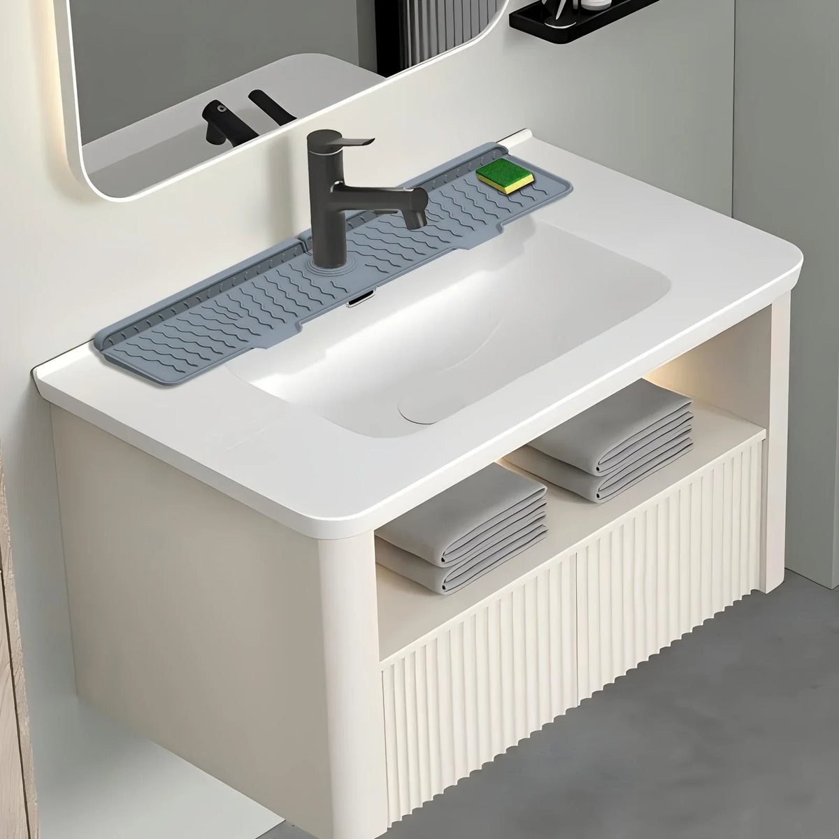 A silicone faucet mat is placed on a kitchen sink, featuring a modern faucet and green accents.