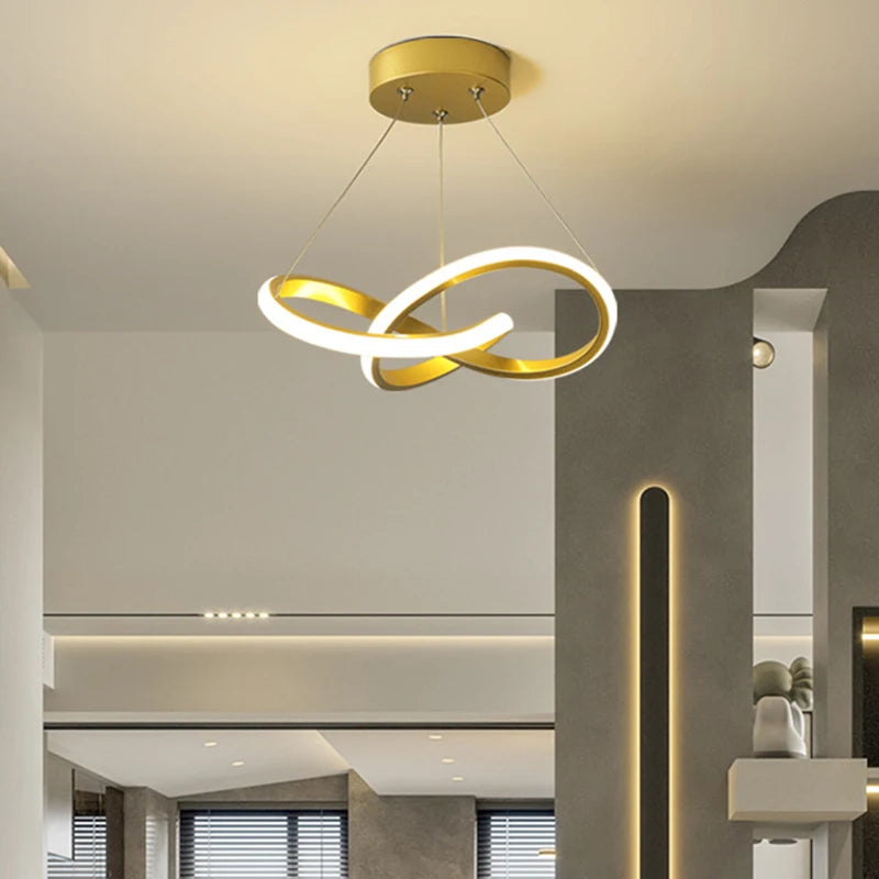 A modern pendant light with a gold finish and a curved white LED design hangs from the ceiling.
