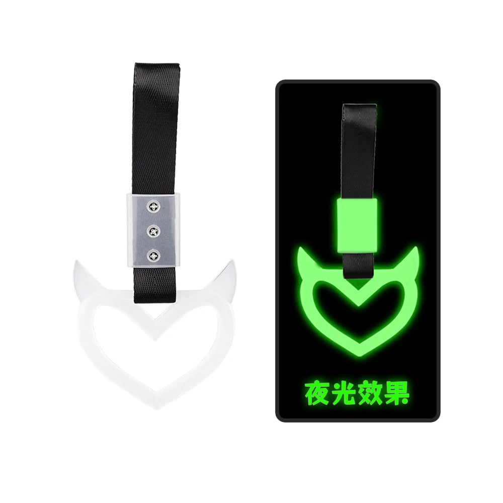 A black strap attached to a glowing green heart-shaped handle for a JDM Tsurikawa ring drift.
