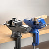 A pair of silver and blue clamp-on vises used to secure objects on a wooden workbench.