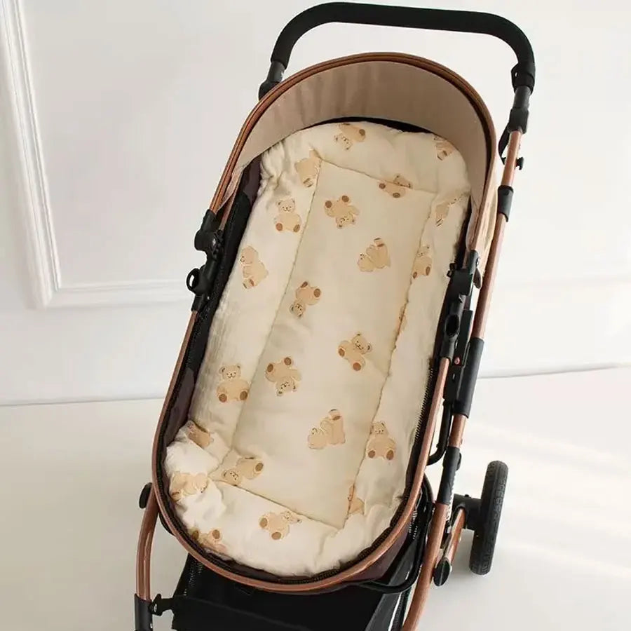 A brown and black stroller with a cream cushion featuring small cartoon bears.