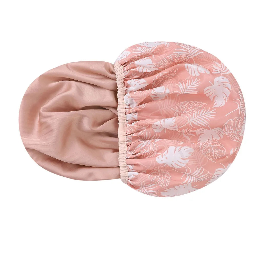 A large pink floral patterned satin-lined waterproof shower cap for hair protection.